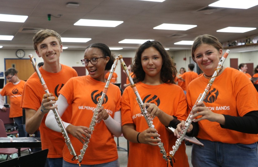 Band students holding flutes to make a W